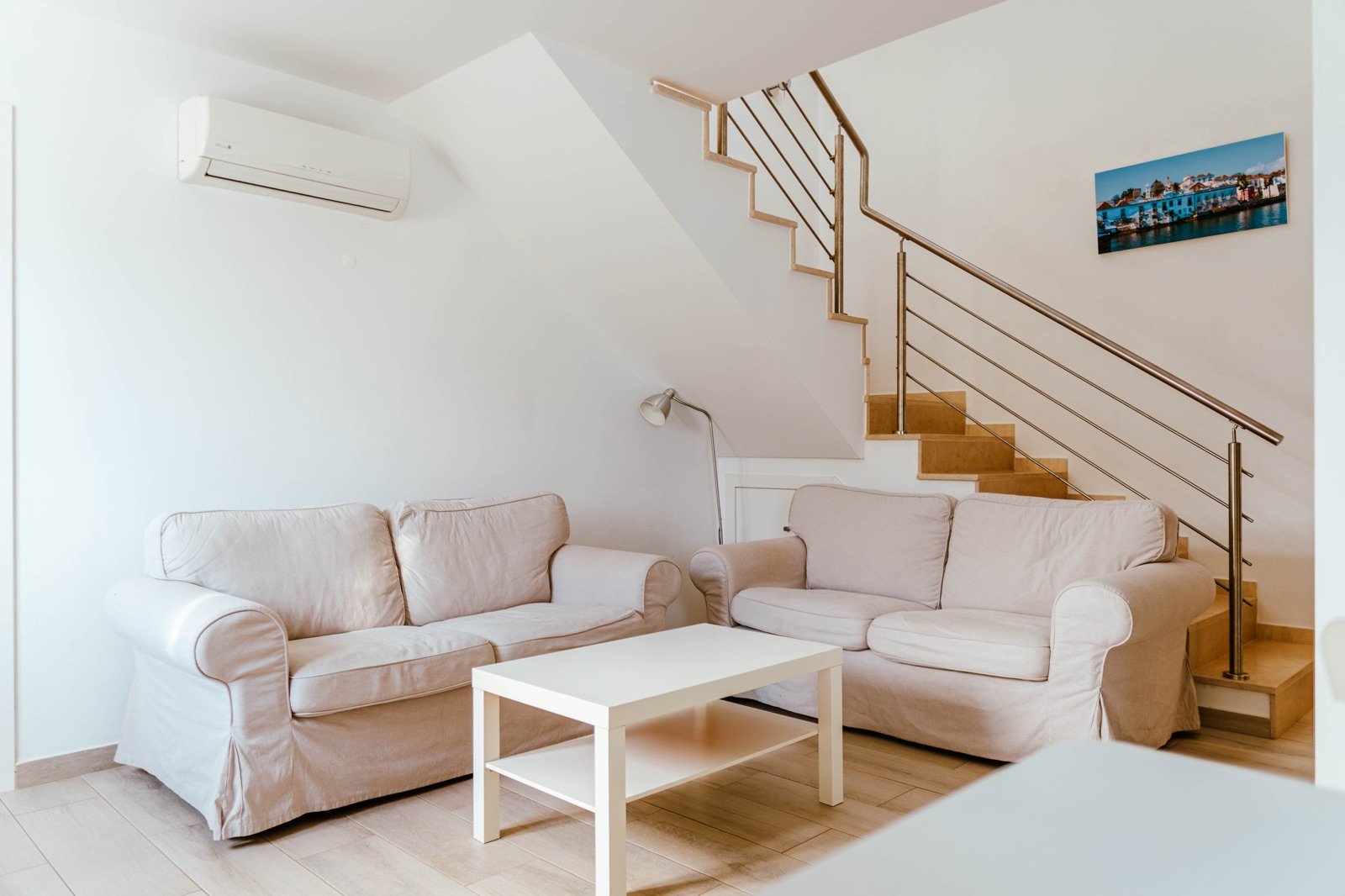 Sala de estar da Casa Lisboa em dois pisos com sofás claros