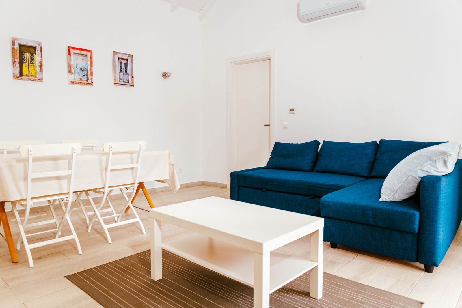 Sala de estar da Casa Tavira com sofá azul e mesa de jantar